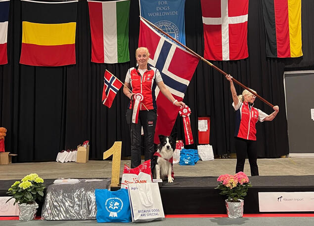 Kvinne og hund på seierspall med norsk flagg